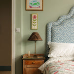 Bedroom with wooden nightstand, lamp, and floral headboard.