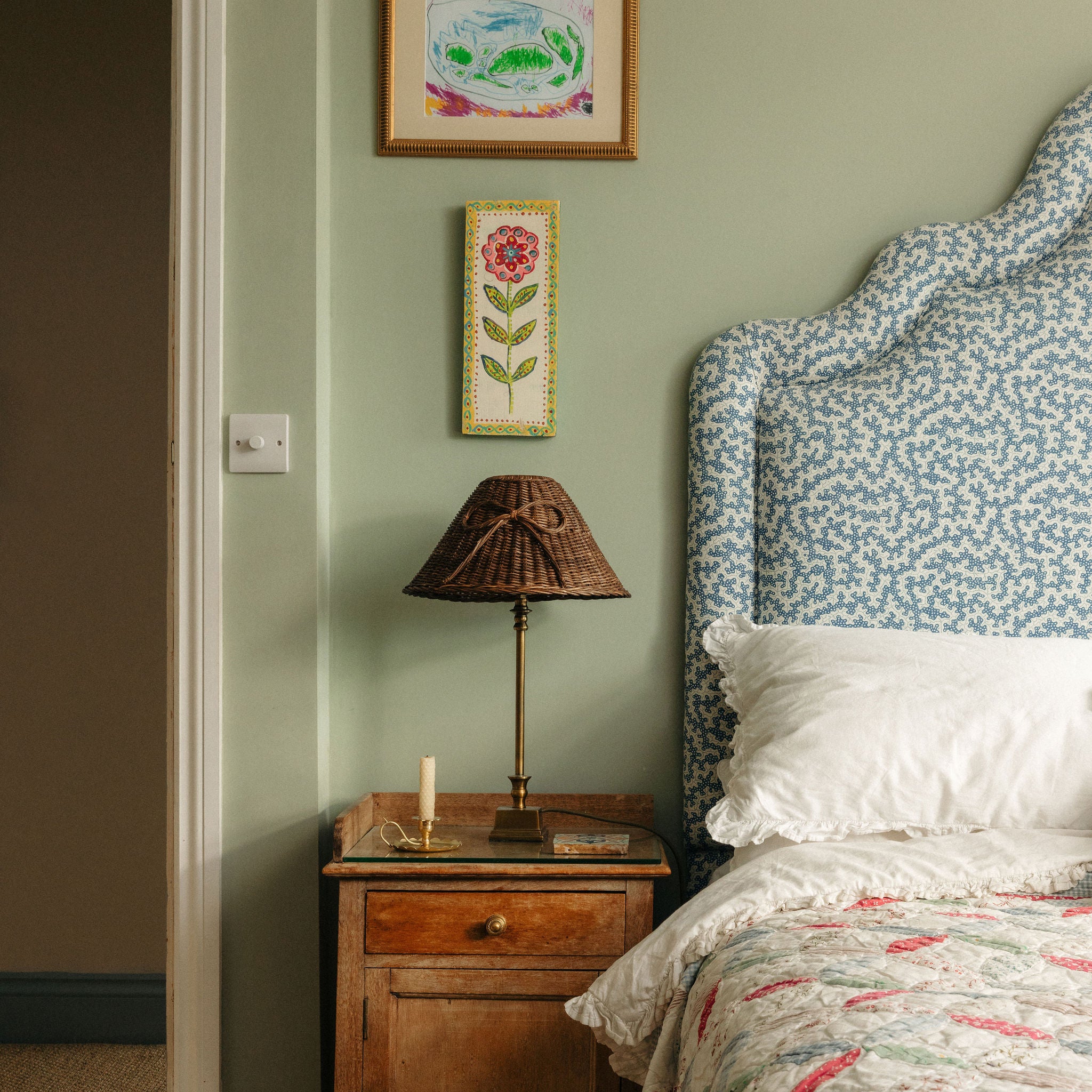 Bedroom with wooden nightstand, lamp, and floral headboard.