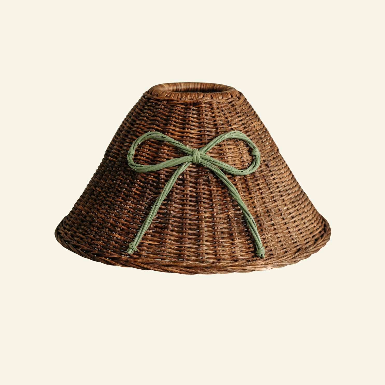 Wicker lampshade with a green ribbon on a beige background