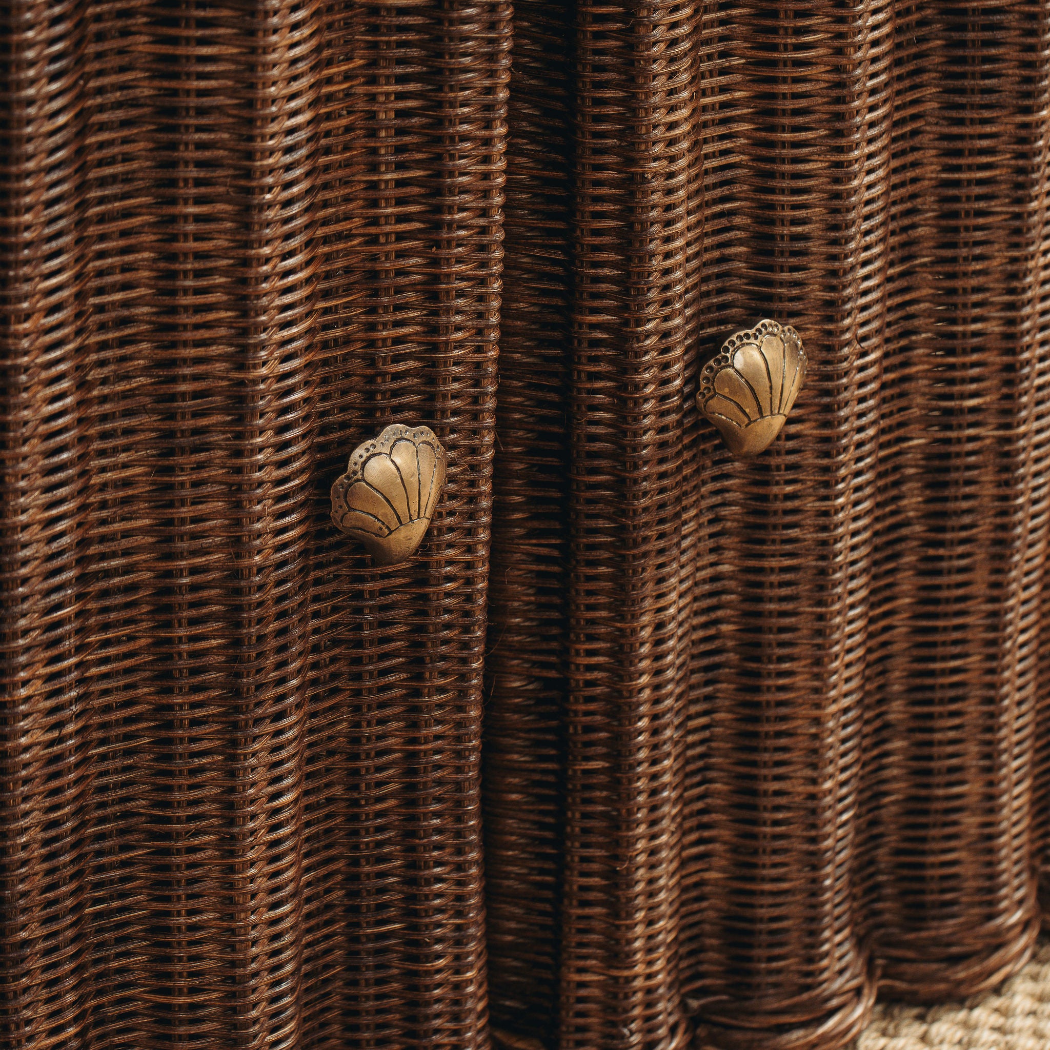 Close-up of woven brown material with butterfly-shaped metal decorations.