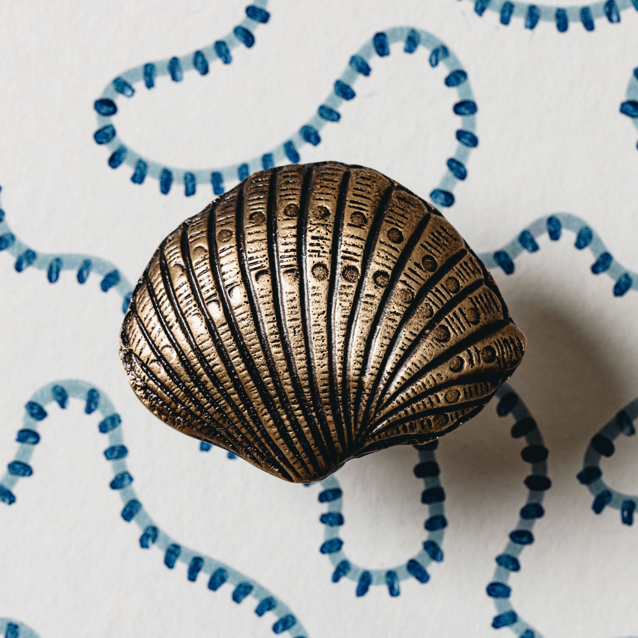 Bronze shell-shaped object on a white background with blue decorative elements