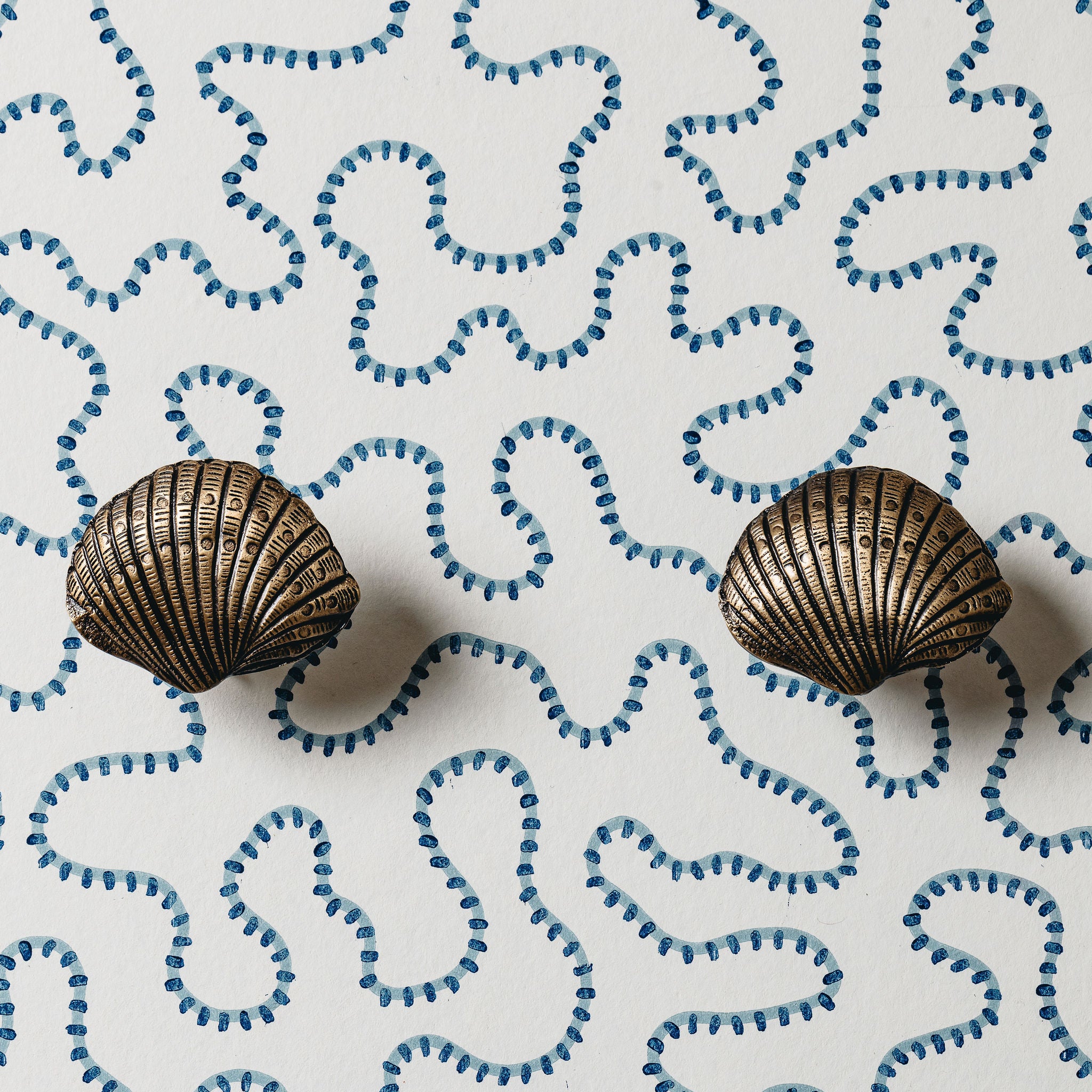 Bronze shell-shaped earrings on a white background with blue shell patterns