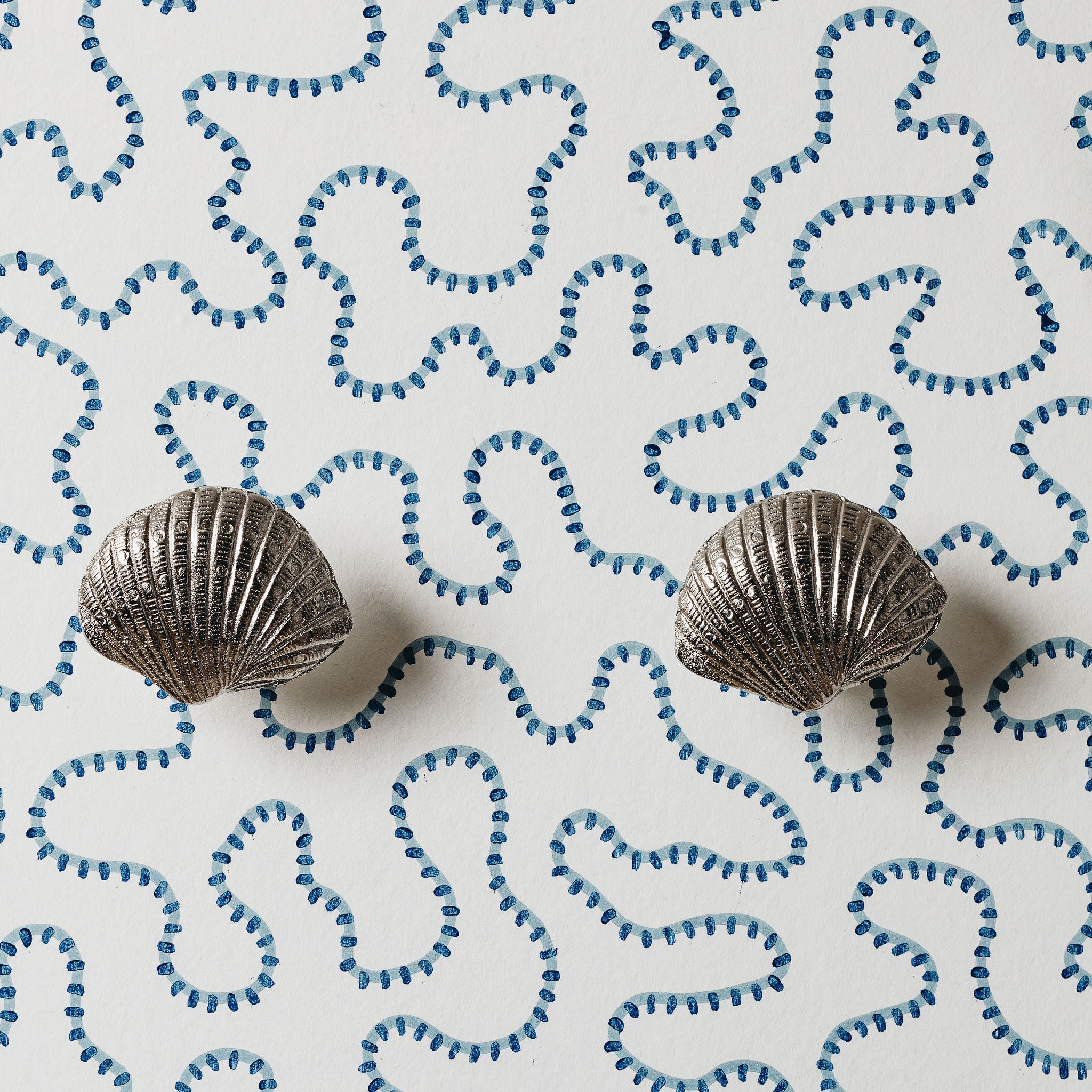 Two metallic shell-shaped objects on a white background with blue wave patterns.