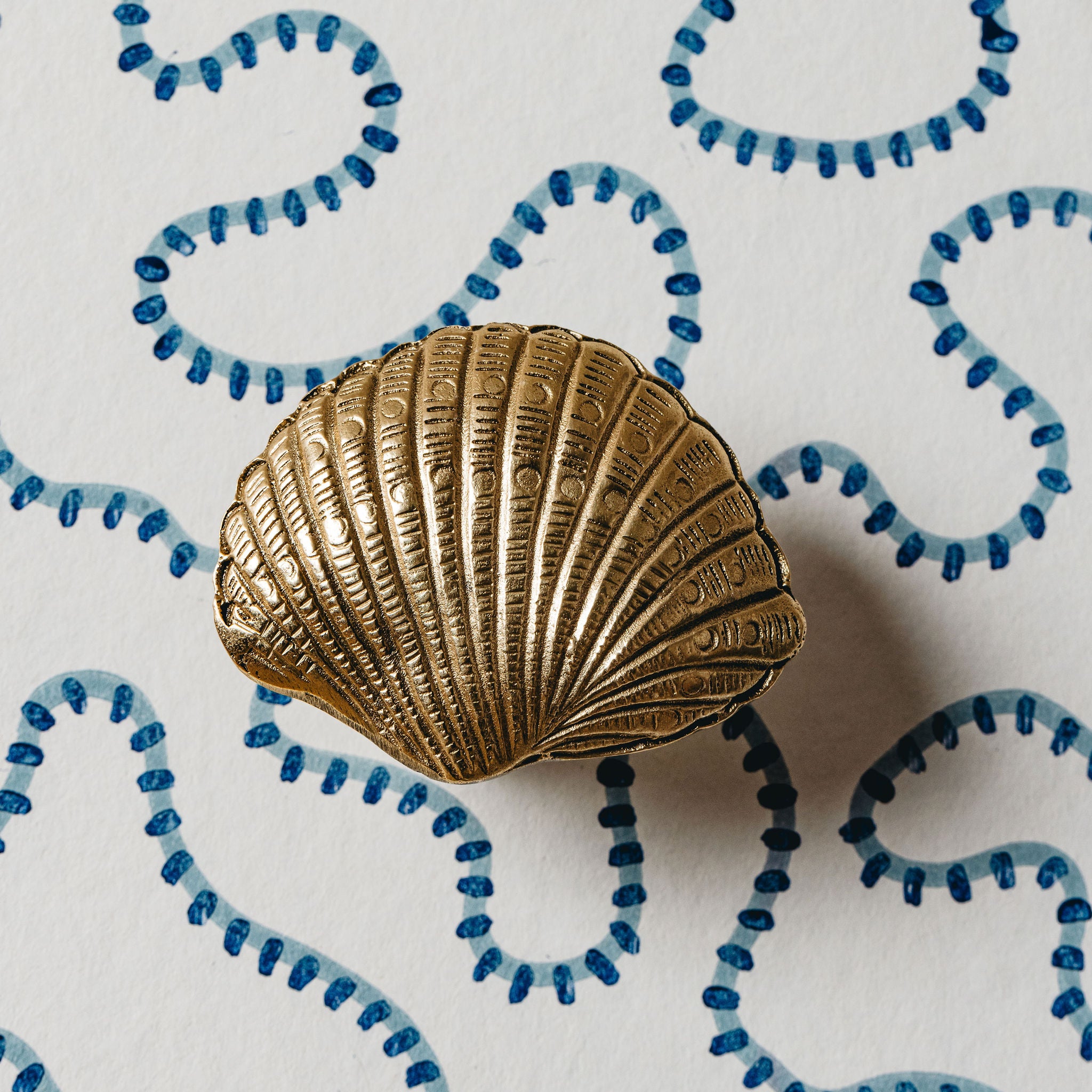 Gold shell-shaped object on a white background with blue decorative elements