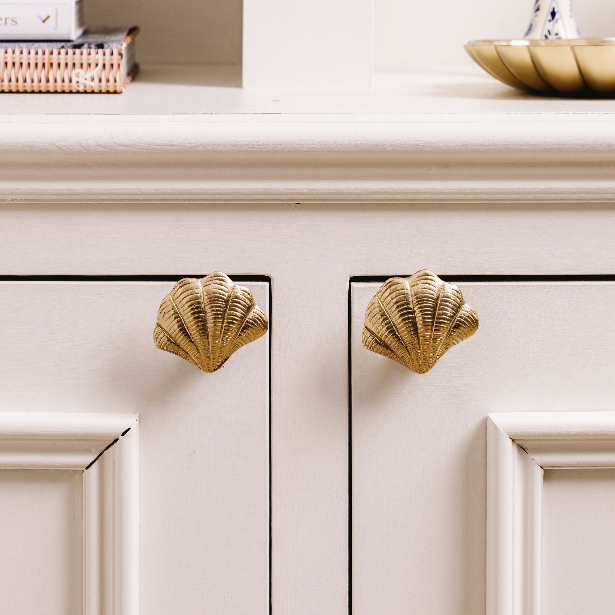Cabinets with gold Curved shell-shaped handles on a neutral background