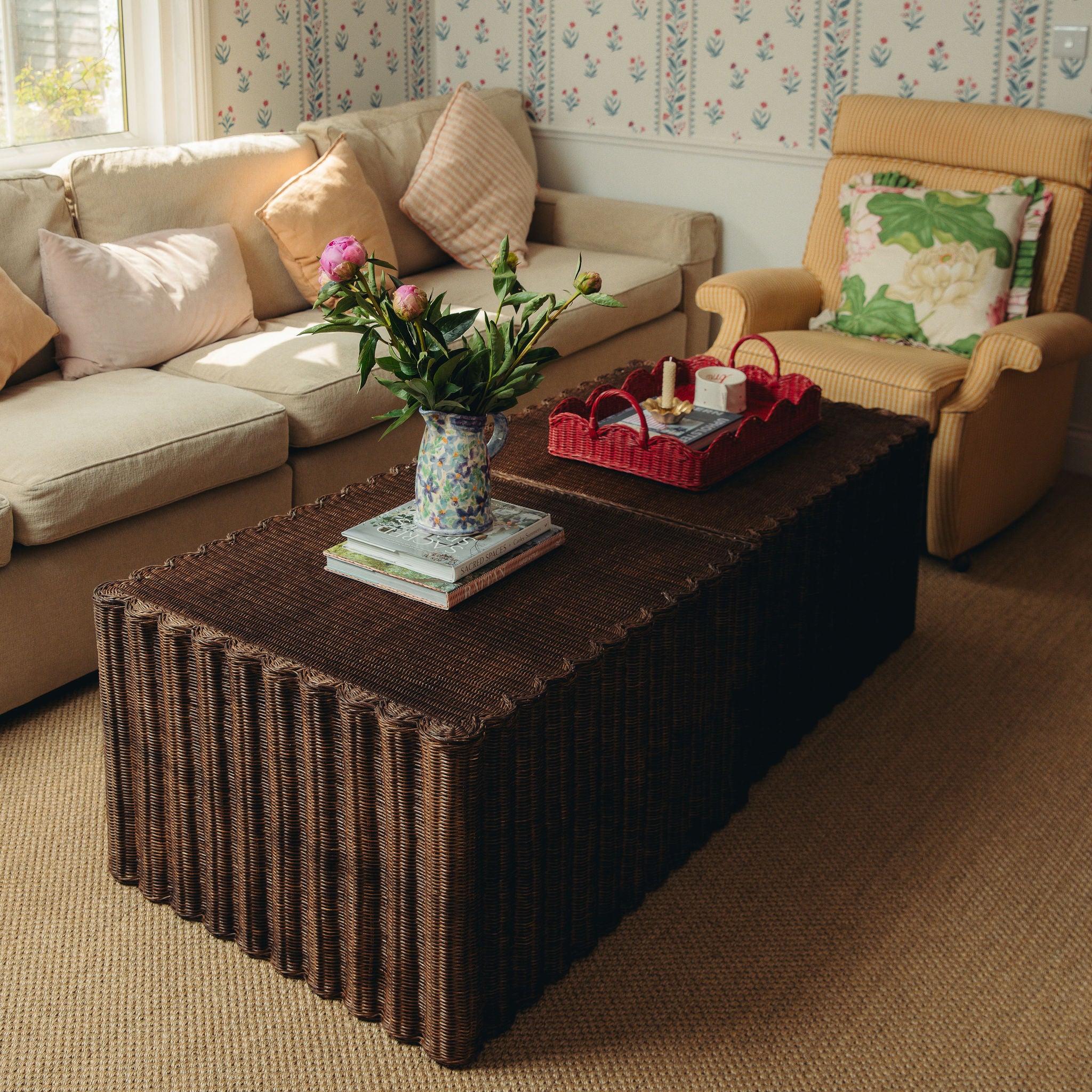 Living room with a wicker coffee table, beige sofa, and armchair with floral cushions.