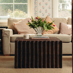 Living room with a beige sofa, Daisy wicker coffee table, and floral arrangement.