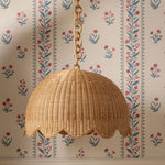 Wicker lampshade hanging against a floral wallpapered wall