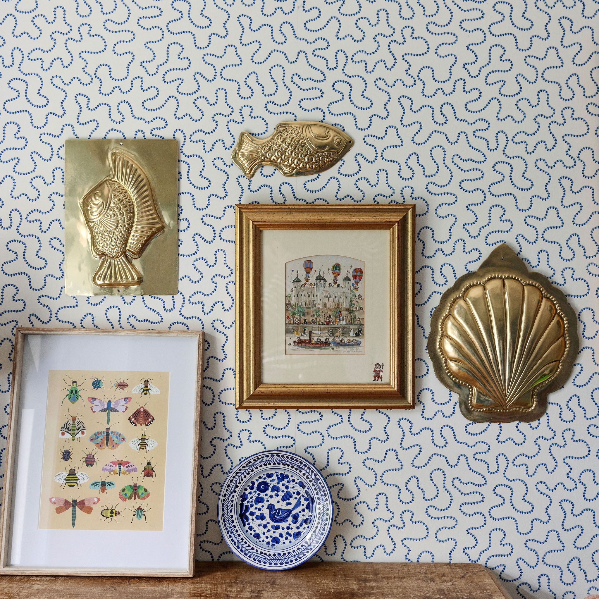 Decorative wall with framed art, shell-shaped decorations, and a lamp.