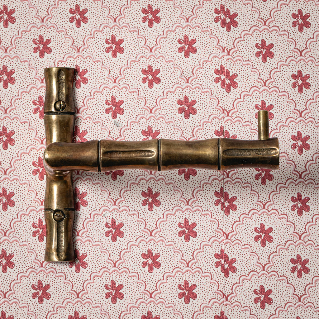 Brass door handle on a floral-patterned wallpaper background