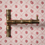 Brass door handle on a floral-patterned wallpaper background