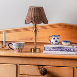 Mimi-scallop-lampshade-small-teak-with-a-lamp-on-a-side-board