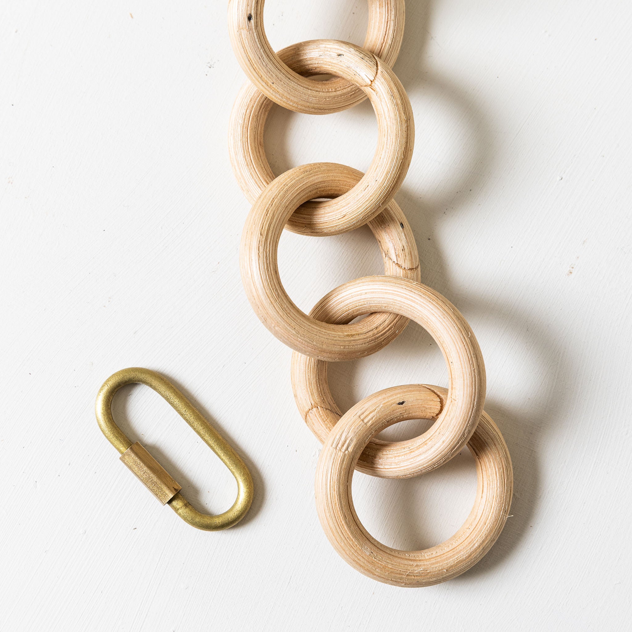 Wooden chain with a brass carabiner on a white background