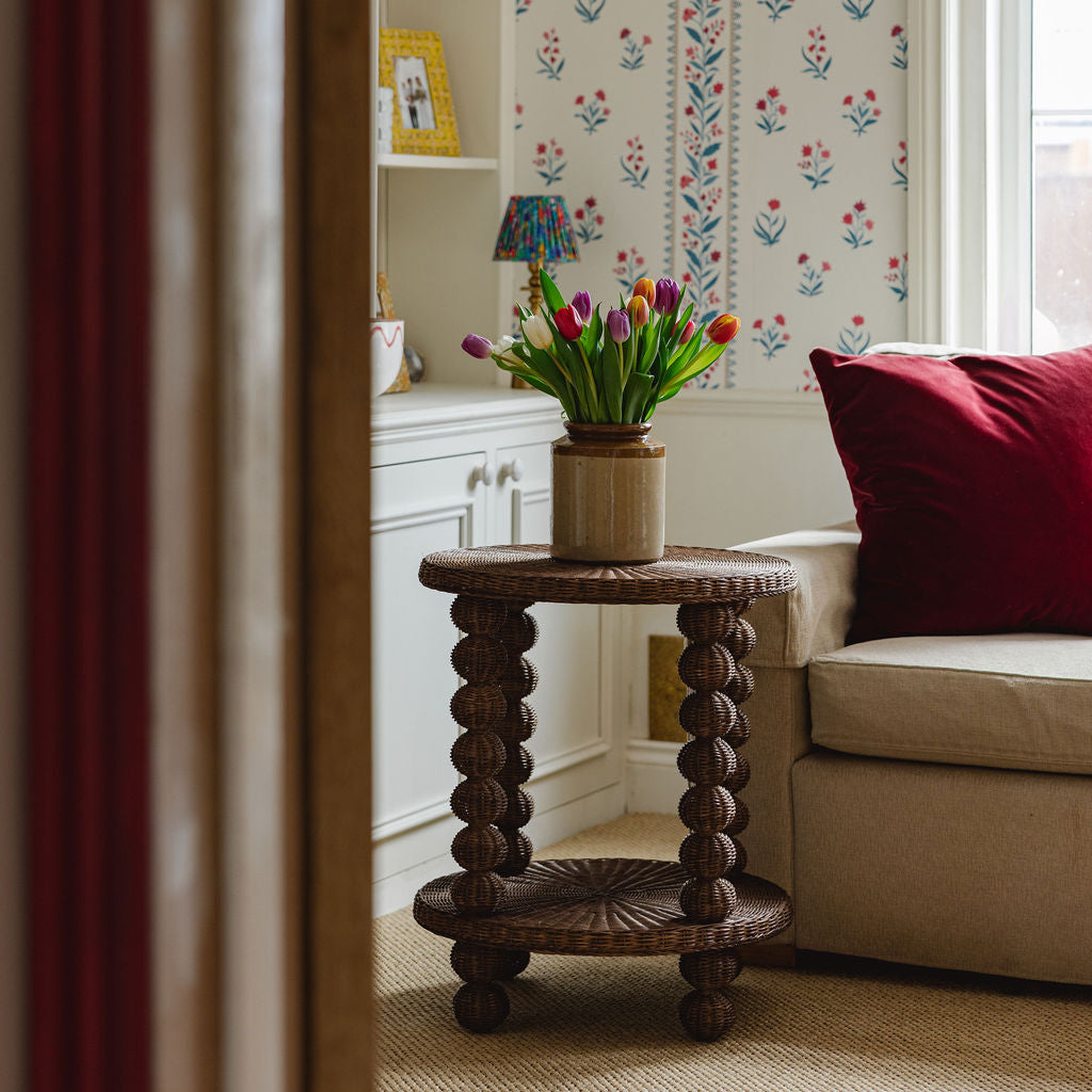 Bobbin side table with a vase of tulips in a living room setting.