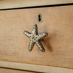Brass starfish-shaped handle on a wooden surface