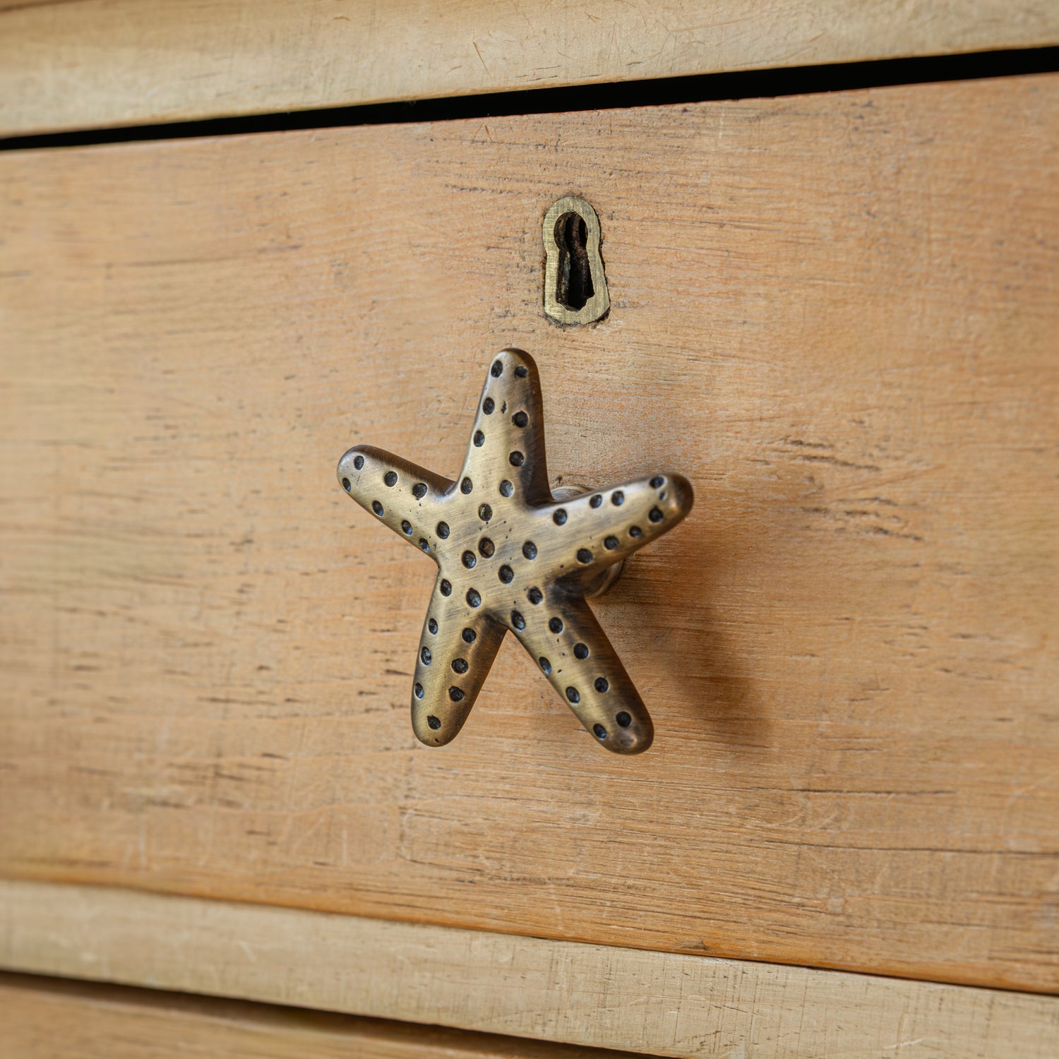 Brass starfish-shaped handle on a wooden surface