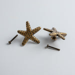 Bronze starfish-shaped knobs with screws on a light gray background