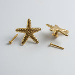 Gold starfish-shaped knobs with screws on a light gray background