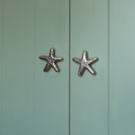 Starfish-shaped cabinet knobs on a light green wooden door
